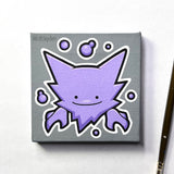 A square mini canvas featuring a Ditto Haunter with white outlines and purple bubbles on a gray background, photographed on a white surface with a paintbrush partially visible at the right edge.