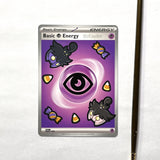 A Pokémon TCG card featuring Pumpkaboos along with Halloween candy painted on, photographed on a white surface next to a pencil.